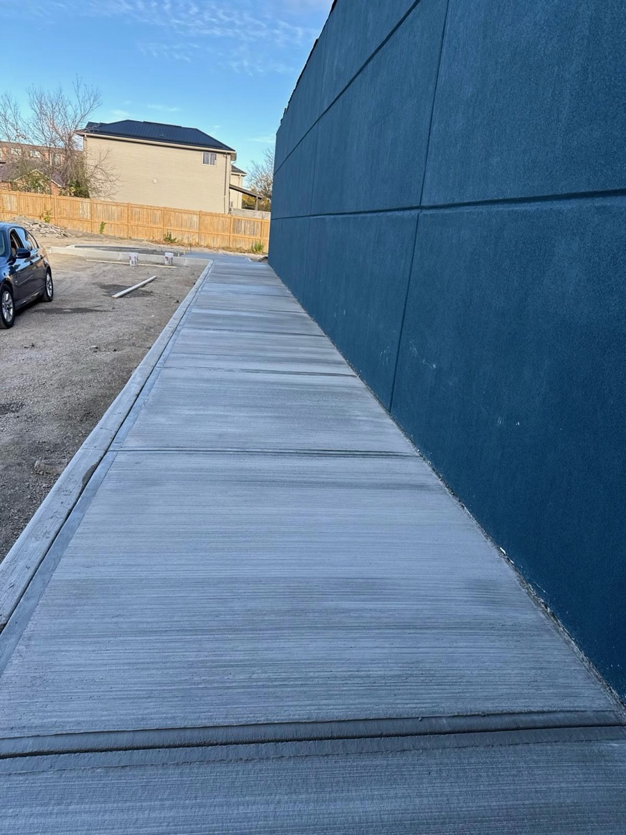 Freshly finished commercial concrete walkway alongside a building